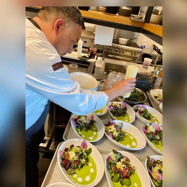 Chef Santos Lugo plating a composed service with disciplined precision before presentation